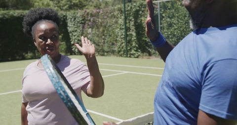 Senior Couple High-Fiving on Tennis Court