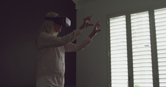 Middle-aged woman experiencing virtual reality with VR headset at home - Download Free Stock Images Pikwizard.com