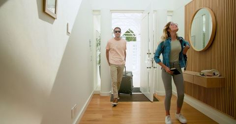 Couple Arriving Home with Suitcase in Bright Hallway