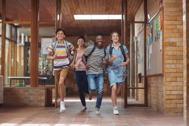 Group of students running down school corridor with happy expressions and backpacks. Ideal for education-related content, back-to-school promotions, or materials emphasizing student life and friendship.