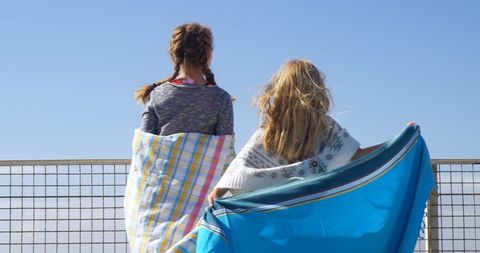 Two Girls in Blankets Overlooking Ocean on Summer Day