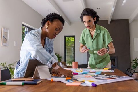 Collaborating on creative layouts with sticky notes and tablet in bright modern home workspace