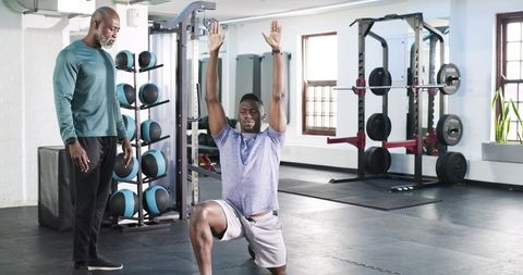 Trainer Guiding Client in Gym Lunge Exercise