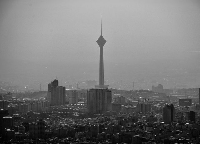 Shows an urban cityscape with prominent tower and high-rise buildings in black and white, conveying urbanization and modern architecture. Milad Tower stands out, making the image ideal for presentations related to travel, architecture, urban studies, or as background imagery highlighting city life and development.