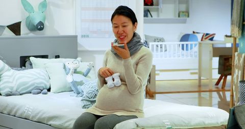 Pregnant Woman Messaging in Cozy Nursery Room