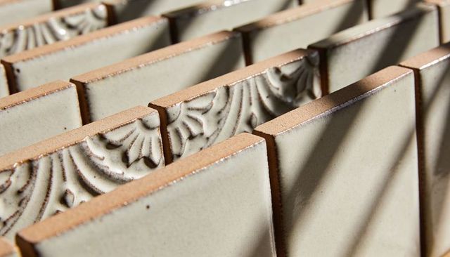 Panning close-up revealing ceramic tiles with embossed motifs and raw terracotta edges