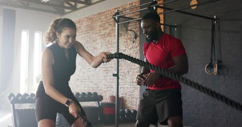 Personal Trainer Guiding Client with Battle Ropes Workout in Gym