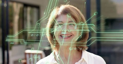 Senior woman wearing eyeglasses with futuristic hud overlay smiling in courtyard daylight