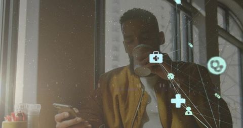 Sunlit urban freelancer sipping coffee while checking smartphone with digital health overlay
