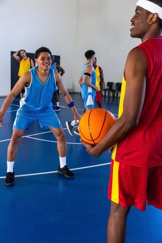 Teens engaged in intense basketball game at indoor court