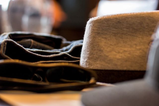 Closeup view of casual clothes along with a hat and sunglasses placed on a table. Useful for fashion websites, lifestyle blogs, and advertisements focusing on casual fashion trends and accessories.