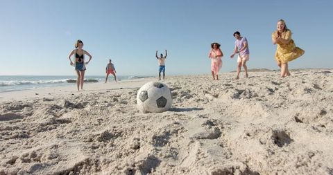 Diverse friends enjoying beach soccer fun together