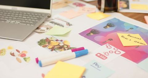 Creative branding mockup workspace showing white markers, sticky notes, laptop and colorful layouts