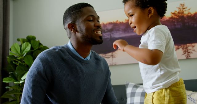 Father bonding with his young son at home, sharing a joyful moment. Perfect for representing family values, parenting, fatherhood, and the positive influence of a loving environment. Can be used in advertisements, articles, or promotional materials related to family activities, education, childcare, and home life.