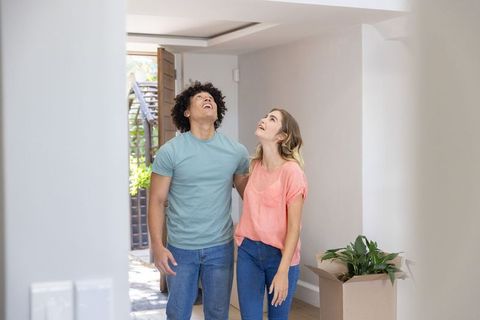 Young couple moving into new home inspecting ceiling in bright entryway