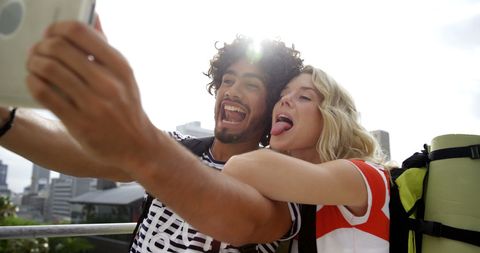 Young Couple Taking Playful Selfie Outdoors with Joyful Expressions