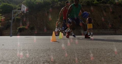 Basketball players dribbling cone drill practicing agility on sunlit outdoor court