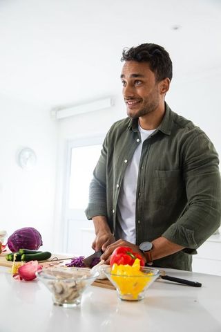 Cheerful Man Cooking with Fresh Vegetables in Modern Kitchen