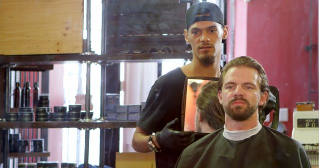 Barber holding mirror to show client fresh haircut while client looks satisfied in modern barbershop, ideal for advertisements, promotions of barbershop services, and hair care products.