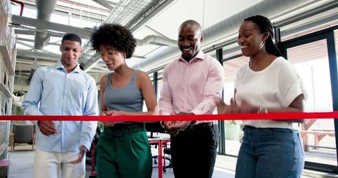 Diverse team celebrating office opening with ribbon cutting