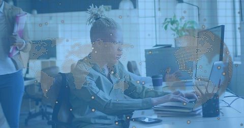 Man with Top Knot Working at Monitor in Modern Coworking Space with World Map Overlay