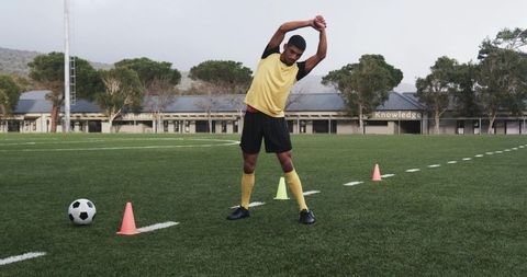 Soccer player stretching on field before training session