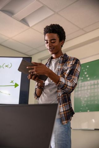 Young man presenting educational graph with digital devices in classroom