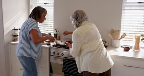 Two senior women cooking together in bright kitchen
