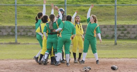 Diverse female softball team celebrating victory on field