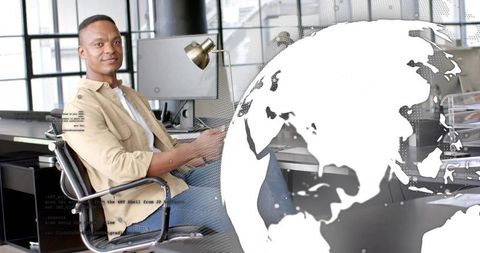 Confident young professional working at modern desk with global digital overlay