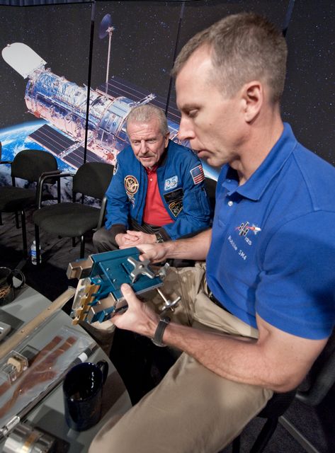 STS-125 Mission Specialist Andrew Feustel, right, shows a part from the Hubble Space Telescope to retired astronaut Loren Shriver, who flew on the Hubble deployment mission STS-31 in 1990, following a press conference, Wednesday, Sept. 9, 2009, after astronomers declared the telescope a fully rejuvenated observatory with the release Wednesday of observations from four of its six operating science instruments at NASA Headquarters in Washington. Photo Credit: (NASA/Paul E. Alers)