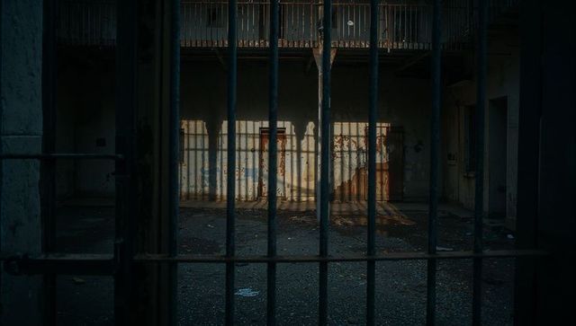 Decaying Prison Cellblock with Barred Gate and Rusted Door