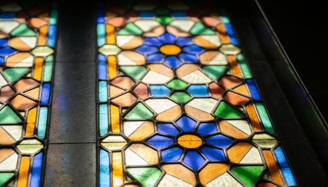 Glowing stained glass panels with blue yellow rosettes and geometric mosaic pattern