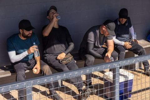 Baseball players resting in dugout drinking water during game break and cooling off