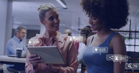 Colleagues collaborating over cracked tablet showing social media overlays and analytics in office