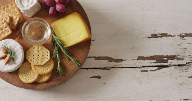 Image of cheese, biscuits, grapes and rosemary on wooden board and rustic table top with copy space - Download Free Stock Photos Pikwizard.com
