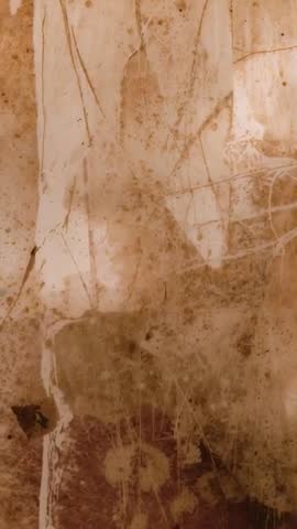 Vertical panning revealing stained plaster wall with floral mark, weathered patina and shifting ligh