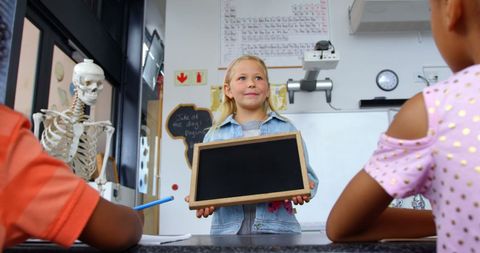 Young schoolgirl teaching with slate in classroom environment