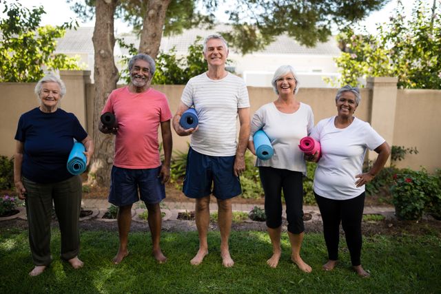 Group of senior individuals holding exercise mats, standing in a park. Ideal for promoting senior fitness programs, community activities, healthy aging, and outdoor wellness events.