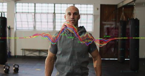 Standing fit trainer in gym with colorful biometric waveform overlay tracking performance