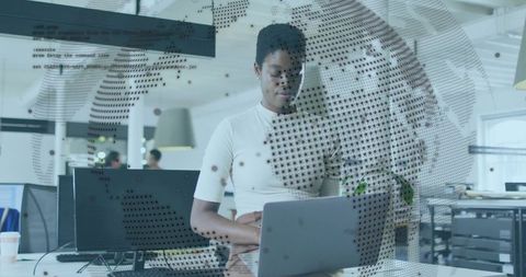 Woman working on laptop in open-plan office with digital data overlay and coding elements