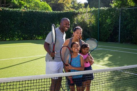Happy Family Playing Tennis Together on Sunny Day