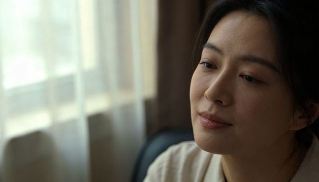 Gazing asian woman reflecting at window with soft curtain light, peaceful indoor portrait