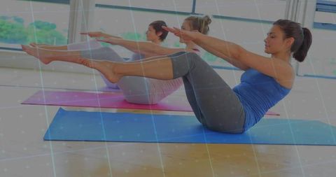 Women Practicing Boat Pose in Light-Filled Yoga Studio