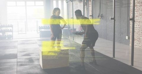 Personal Trainer Coaching Athlete with Tablet for Box Jump Workout in Sunlit Gym