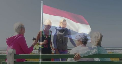 Women embracing fitness with dutch flag symbolism by seaside