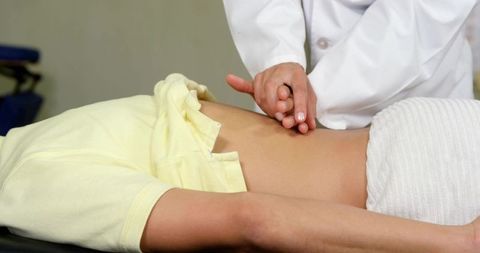 Doctor palpating patient abdomen during routine medical exam, clinical abdominal checkup