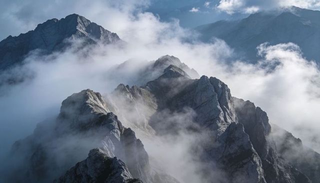 Misty Jagged Alpine Ridgeline Cutting Through Low Clouds and Mountain Mist
