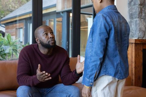 African american father having serious conversation with son on cozy living room couch