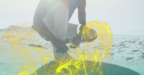 Fit man tying shoelaces with digital effects at beach